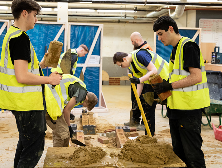 Adults learning how to lay bricks