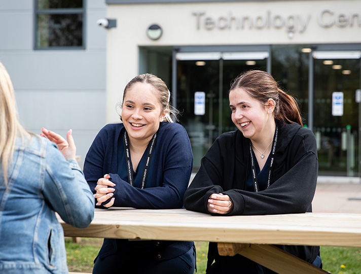 3 Students siting outside the tech Block at Bromley Campus